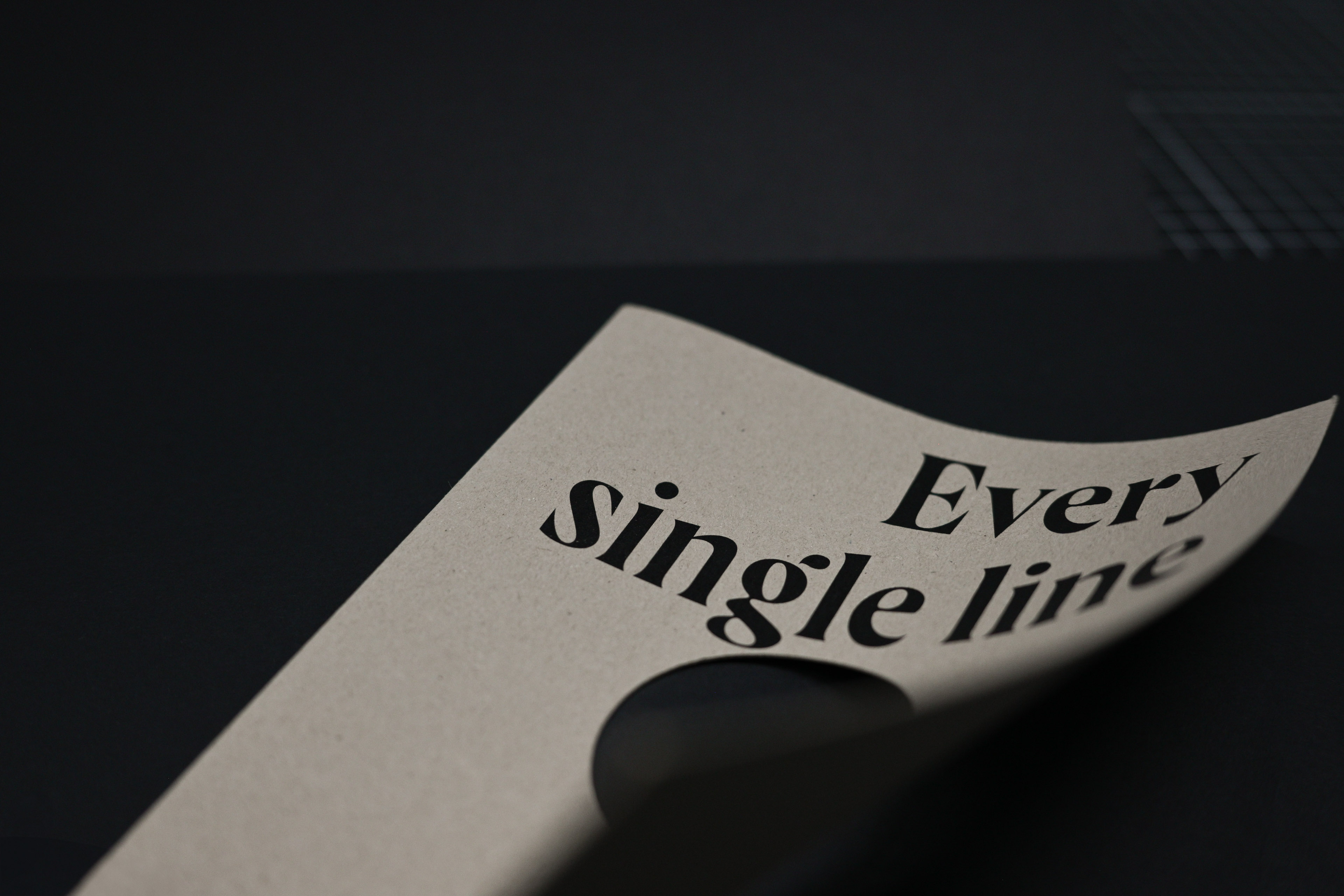 Hellbraune Broschüre mit schwarzem Text „Every single line” auf dunklem Untergrund und Stanzung.
