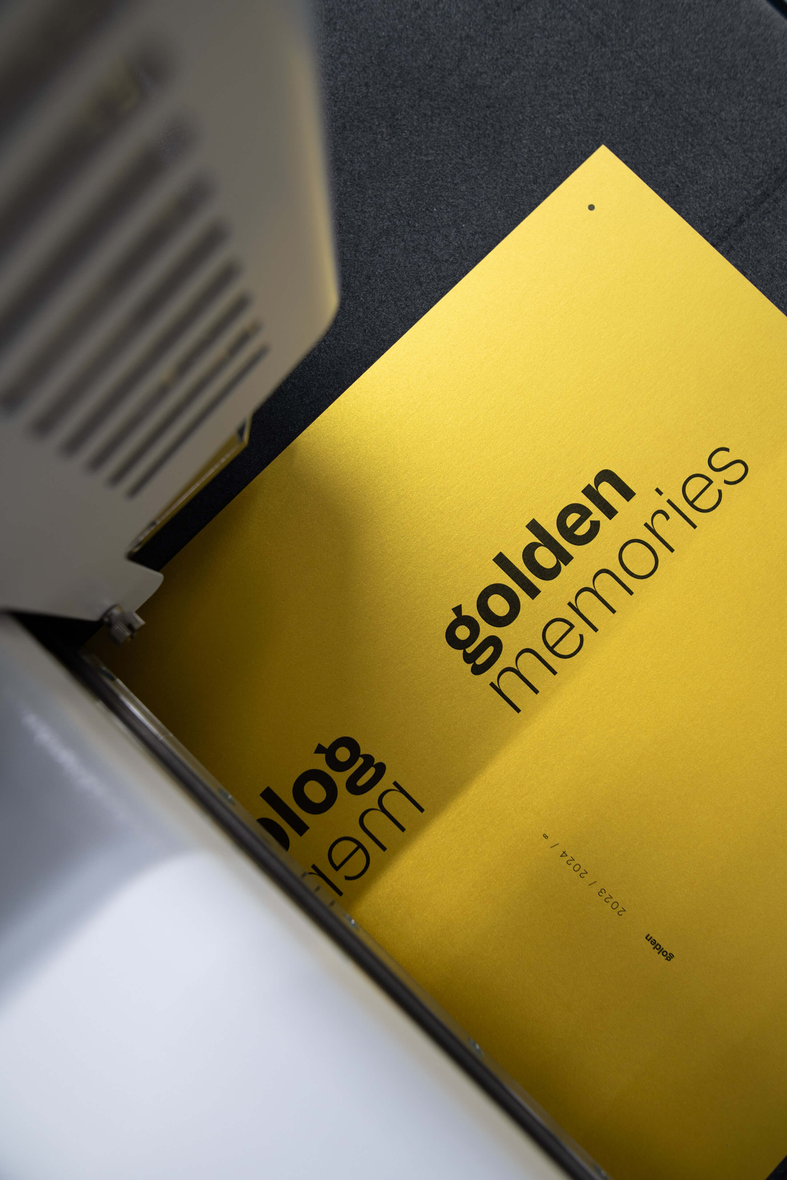 Nahaufnahme eines goldenen Papiers mit dem Text „golden memories“, das durch eine Schneidemaschine verarbeitet wird.